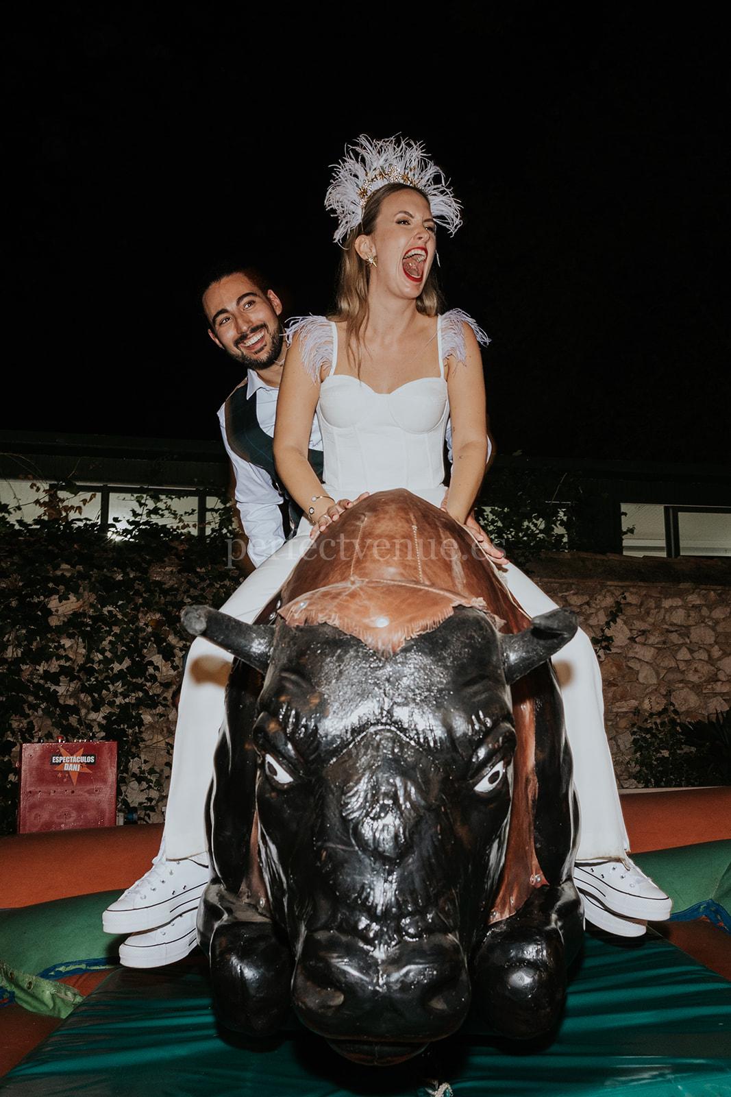 Bride and groom on mechanical bull / Photo via Silvia Sánchez Photography