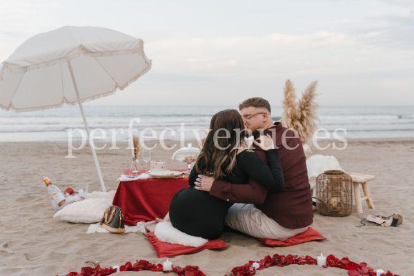 marriage proposal with a picnic and petals in the beach - Photo via Weddings and Events by Natalia Ortiz