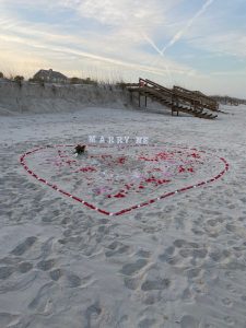 Una pedida de mano en Cádiz con corazón de pétalos de rosa en la playa