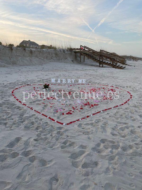 Una pedida de mano en Cádiz con corazón de pétalos de rosa en la playa