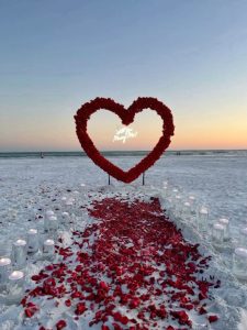 A marriage proposal in Cadiz with a large flower heart on the beach / Photo via Natalia Ortiz Events
