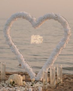A marriage proposal in Cadiz with a large flower heart on the beach / Photo via Natalia Ortiz Events