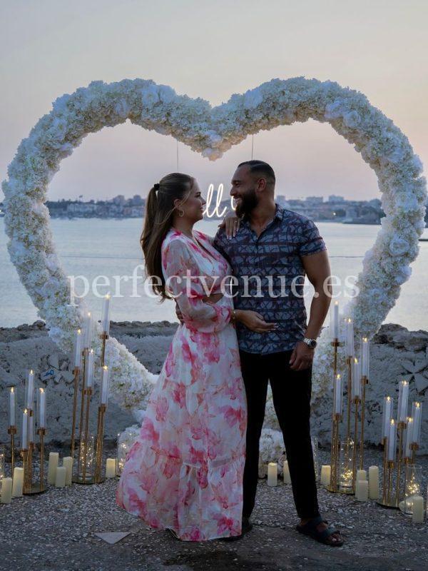 A marriage proposal in Cadiz with a large flower heart on the beach / Photo via Natalia Ortiz Events