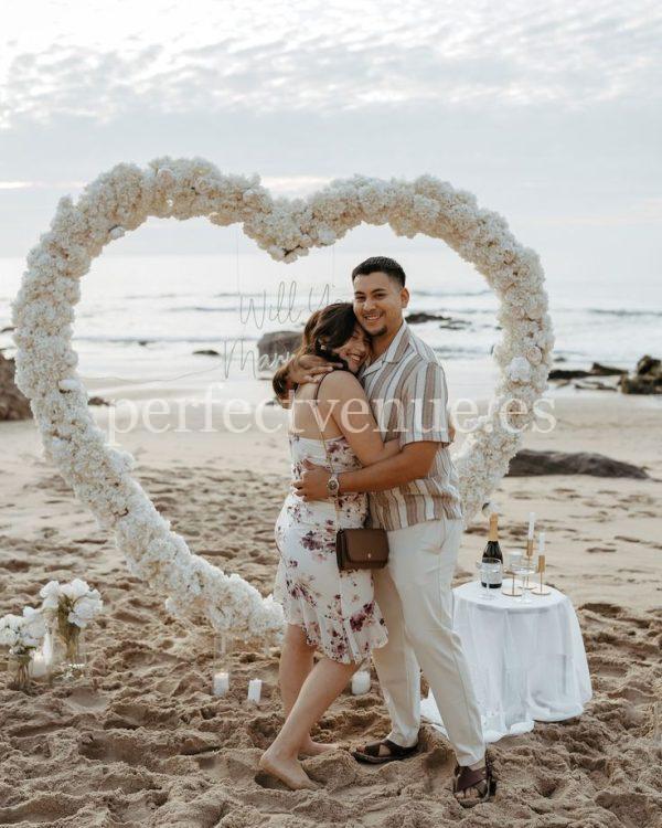 A marriage proposal in Cadiz with a large flower heart on the beach / Photo via Natalia Ortiz Events