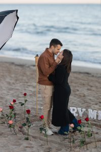 Beach proposal with roses and "Marry Me" lettering / Photo via Natalia Ortiz Events